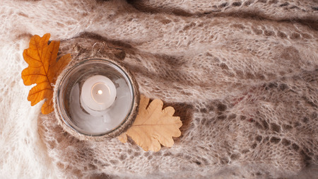 Cozy wool winter autumn fall accessory. Warm pleid and candle on a wooden table/ Authentic Tranquil Atmosphere. Kinfolk Hygge Slow Living Style. Top viewの写真素材