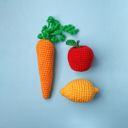 Set of knitted toys lemon, carrot, apple on blue background. Earlier tactile development of children, craft toys, vegetarian menu conceptの写真素材