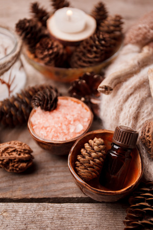 Spa and wellness setting with sea salt, oil essence, cones and candle, wooden decor on wooden background. Fall autumn winter wellness concept, Relax and treatment therapy.の写真素材