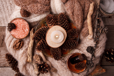 Wood scents for winter time aromatherapy. Pine cones, candles, essential oil bottles, top view. Spa relax winter concept, copy spaceの写真素材