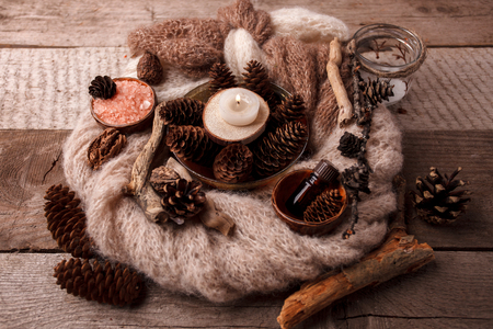Spa sauna composition on wooden table. Natural aroma oil, sea salt, cones, candles, wooden decor on rustic wooden background. Healthy skin care. SPA concept.の写真素材