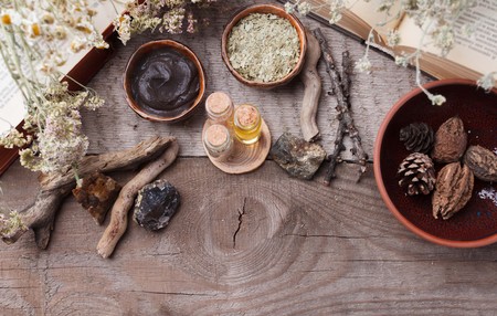 Preparing cosmetic black mud mask on vintage wooden background. Top view of facial clay on table with sea salt, spa products and dry flowers. Natural cosmetics for home or salon treatment, copy spaceの写真素材