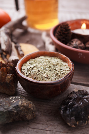 Healthy tea, dry herbs, plants, candle and stones on wooden table. Homeopathy and herbal alternative medicine.の写真素材