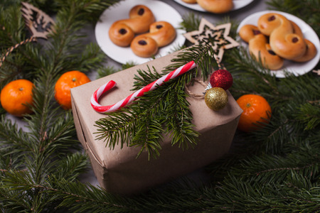 Swedish traditional saffron buns, also known as lussekatter or lussebullar. The yellow buns have raisins and are shaped in spirals and gift box xwith candy cane, xmas closeupの写真素材
