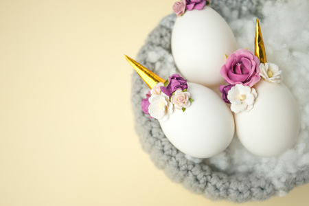 Easter holiday concept with cute handmade eggs, unicorn and flower decoration in bird nestの写真素材
