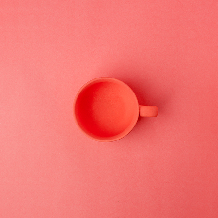Color of year 2019 Living Coral concept. Ceramic cup on living coral background, monochrome morning breakfast minimal conceptの写真素材