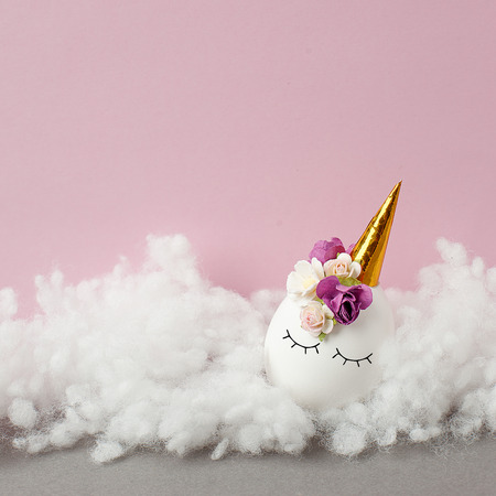 Easter holiday concept with cute handmade eggs, of kawaii cute sleepy unicorn egg on fluffy cloudの写真素材