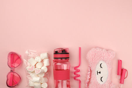 Set of Feminine accessories with sunglasses, sleep band, bpa free bottle for water, plastic straw, hygiene tampon and marshmallow sweetness on pinkの写真素材