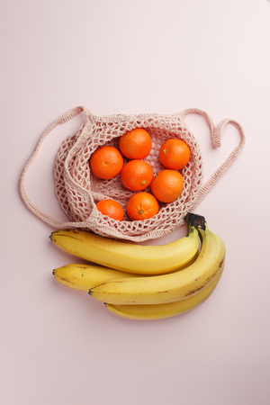 Fruits tangerine, banana in recycling net market bag on whiteの写真素材