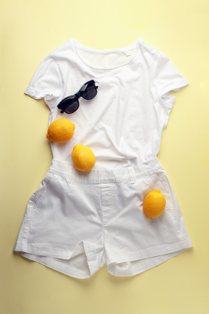 White jeans, white shirt, sunglasses and lemons on yellowの写真素材