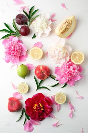 Colorful food pattern made of lemon, melon, plum, peach, grapefruit and beautiful peoniy flowers. Flat lay.の写真素材