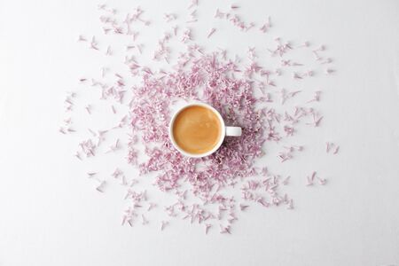 Morning breakfast with coffee cup and lilac flowers on white background. Flat lay, top view women...