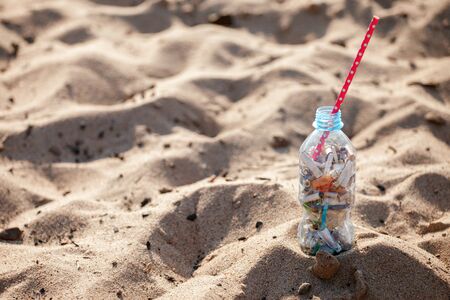 Cocktail with garbage and straw on clean beach. Plastic ocean pollution, environmental crisis. Say no plastic. Single-use plastic waste, world ocean day, eco conceptの写真素材