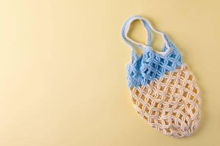 top view of empty yellow blue string bag on yellow background, zero waste eco-friendly trendy...