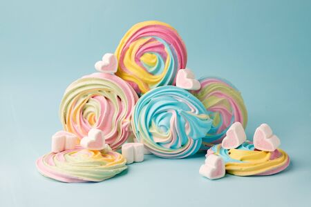 Pink marshmallow in heart shape and rainbow merengue on blue. Sweet candy for love theme on...