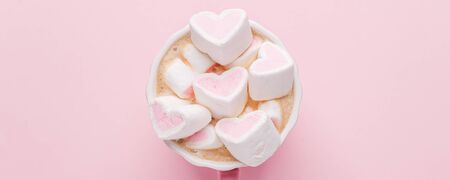 Minimalistic Romantic desk top with cup of coffee and pink heart shaped marshmallows. Saint valentines wedding birthday composition. Top view. Banner copy spaceの写真素材