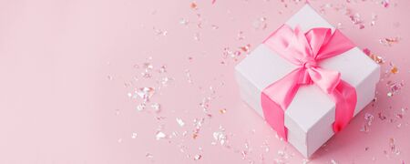 White gift box and confetti on pink background with copy space for text. fashion and shopping concept. wedding, marriage or birthday composition. flat lay, top viewの写真素材