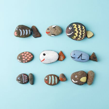 Multicolored stones and creative fish made of stone. The painting is painted in different colors in texture style on blue, DIY, kindergarten, daycare creative art, hobbyの写真素材