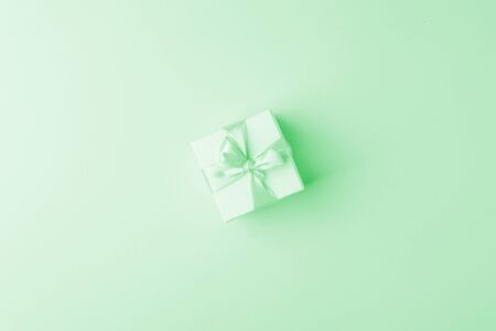 Present or gift box with satin bow on pink paper background, top view. Valentines day greeting card, black friday sale, congratulations concept. Flat lay, neo mint pastelの写真素材