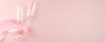 Valentines day greeting card. Empty Wine glasses for wine and ribbon on a soft light pink background. Flat lay, top view, copy space, minimal february  romance concept, bannerの写真素材
