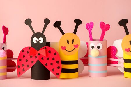 Paper toy insect for valentine romance baby shower, birthday party. Easy crafts for kids on pink background, copy space, die creative idea from toilet tube roll, recycle reuse eco