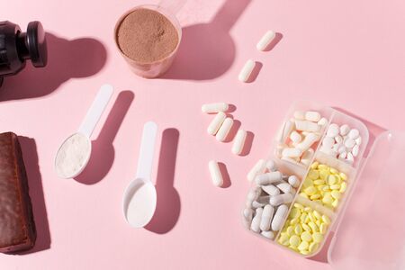 Therapeutic percussive massage gun, fit meal, pills, sport energy bar on pinkの写真素材