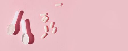 Protein powder, scoop, energetic muesli bars, vitamin pills, gainer on pink