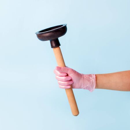 Hand in pink glove holding domestic plunger.の写真素材