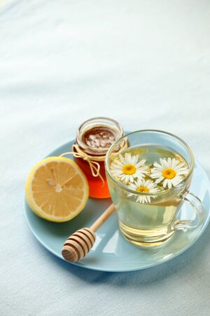 Chamomile flowers and chamomile tea. Chamomile tea in glass teacup with flowers, honey and lemon, top view, prevention of seasona flu colds