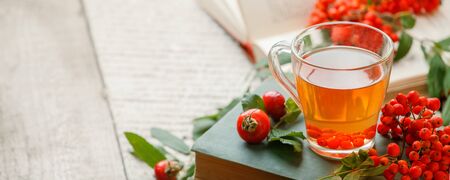 Autumn fall leaves, a cup of tea and opened book on wooden tableの写真素材