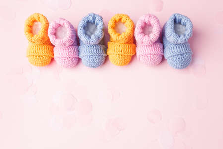 Pregnancy motherhood perenthood concept, Three pairs of baby booties on pink backgroundの写真素材