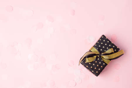 Stylish gift or present box with gold bow on pink pastel background, seasonal holiday sale concept,...