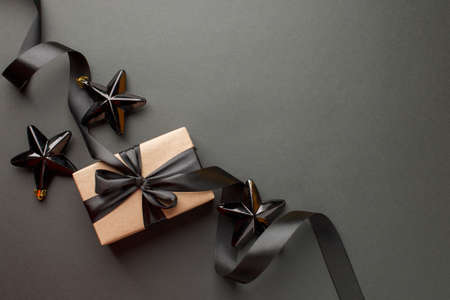 Beautiful minimal christmas golden black decor and paper craft gift box with satin black ribbon on...