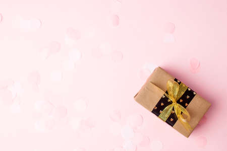 Stylish gift or present box with gold bow on pink pastel background, seasonal holiday sale concept,...