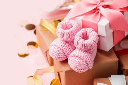 Beautiful composition with pink baby booties and gift box on pink background. Concept of baby shower party, first birthday holiday card, copy spaceの写真素材