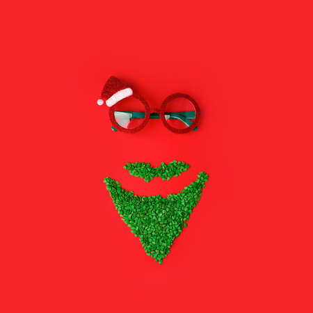 Santa Claus minimal concept. Christmas New Year flat lay. Funny carnival sun glasses and green sweet sprinkles on traditional red background, minimal creative concept, winter holiday flyer, couponの写真素材