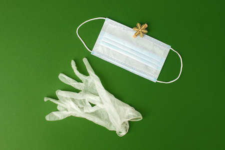 Latex Gloves, medical facemask with gold decor on natural green background. Party concept, winter...