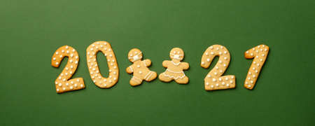 Happy New Year's set of cookies, gingerbread man and woman in face mask, number 2021 biscuits glazed sugar decoration on green background, minimal seasonal pandemic winter holiday bannerの写真素材