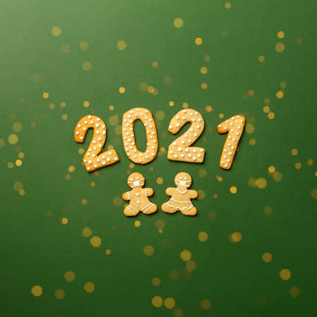 Happy New Year's set of cookies, gingerbread man and woman in face mask, number 2021 biscuits glazed sugar decoration on green background, minimal seasonal pandemic winter holiday flyerの写真素材