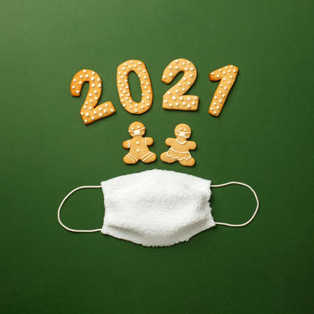 Happy New Year's set of cookies, gingerbread man, woman in face mask, number 2021 biscuits glazed sugar and funny white facemask on green background, minimal seasonal pandemic holiday flyerの写真素材