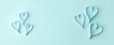 Paper hearts over the blue pastel background, copy space. Abstract background with paper cut shapes. Sainte Valentine, mother's day, birthday wedding greeting cards, invitation, celebration bannerの写真素材