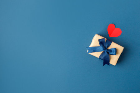 Paper craft gift boxes with bow on blue background with hearts, copy space. Greeting card concept. Saint Valentine, romance, Dad day, wedding, new year, birthday, wedding, mother dayの写真素材