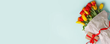 Traditional Romantic background with bouquet of red tulips and gift box on blue. Top view with copy space, banner, flyer, invitation. Mother's Day, 8 March, Happy Easter backgroundの写真素材