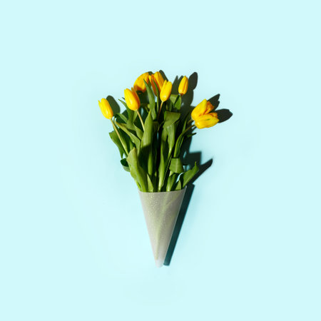 Yellow tulip flowers bouquet with hard shadow on blue background, copy space. Banner for seasonal holiday, springtime concept, International Woman day, 8 march, Happy Easter greeting flyer, invitationの写真素材