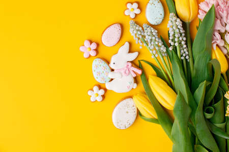 Happy Easter. Multi-colored pastel easter cookies gingerbread, seasonal flowers tulips on bright...