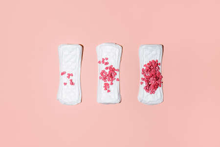 Feminine hygiene sanitary pads with confectionery heart on pink background, top view. Concept of critical days, menstruation, woman healthcare, hard shadow trendy card, flyer, invitation, couponの写真素材