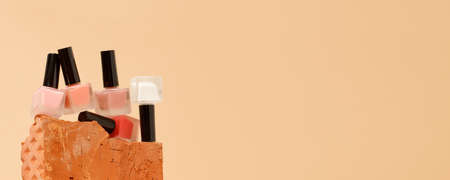 Set of nail polish bottles neutral natural colors on brick podium on beige background. Concept of pallete for french manicure, trendy modern stone platform for presentation of productsの写真素材