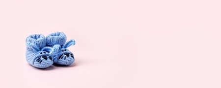 Cute blue newborn baby boy shoes with funny bunny rabbit decoration over pink background. Baby shower, birthday, invitation or greeting card idea, copy space, banner, header. Handmade clothの写真素材
