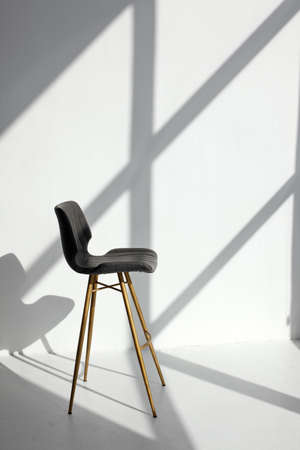 Empty modern chair in room, stine sunlight, white walls. Minimalistic interior, concept of cleanliness, loneliness, calm, cleansing, copy space, stylish trendy studio mock upの写真素材