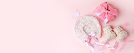 Beautiful composition with baby booties shoes, bonnet and gift box on pink background. Concept of baby shower party, pregnancy, mother day, first birthday holiday card, copy space, bannerの写真素材